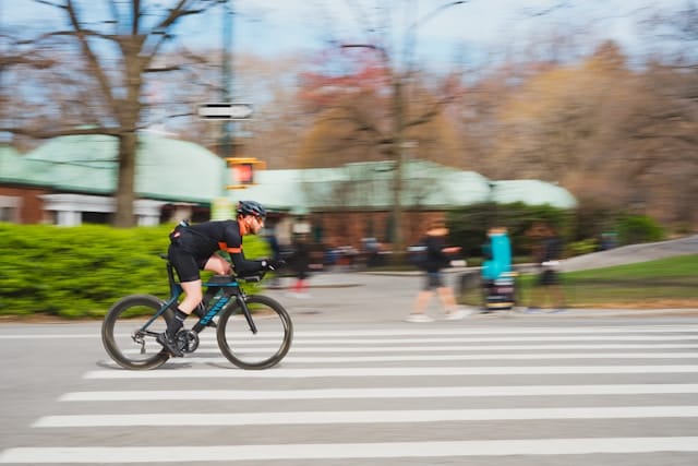 Man biking quickly past onlookers in a park