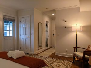 Private entrance door and full-length mirror in Room 16 at Stanton House Inn, with bathroom entry visible