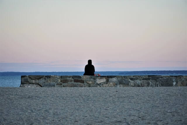 person sitting on a rock wall overlooking the water at Cummings Park