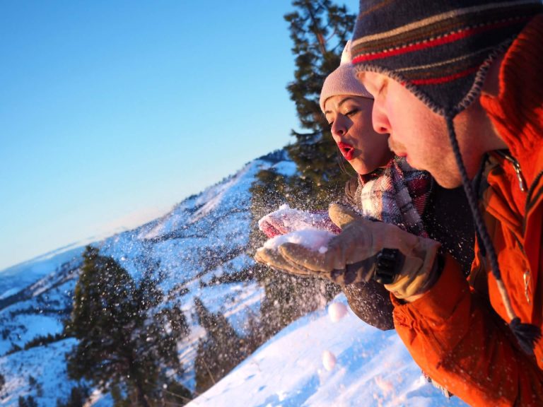 couple blowing snow while enjoying their winter vacation at one of the best places to visit in CT for winter getaways