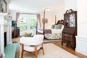 King Suite With A Clawfoot Tub: The Brush Suite 26 Shot of the fireplace seating area, antique secretary, and king bed in the Brush Suite