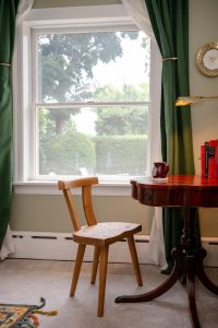 Modern, handcrafted teak chair at the antique library table workspace by the window