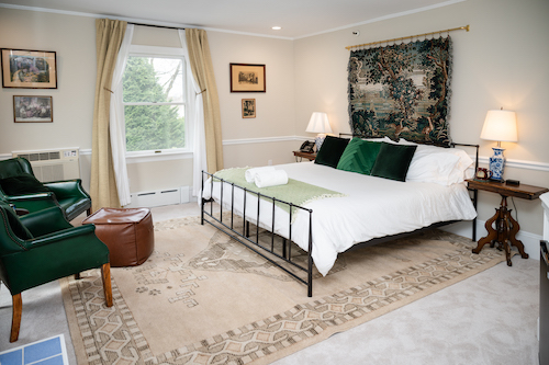 Room 14 has a cozy seating area, king bed, and a tapestry behind the bed frame