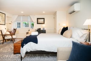 A view of Room 5 from the TV Lounge area looking towards the king bed, seating area by the window, and dressing area.
