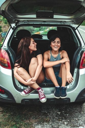 Two road trip travelers enjoying a pause on the journey before putting on their hiking boots for a trail