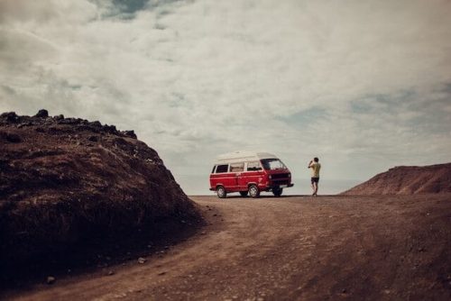 A man stopping to take a photo next to his camper van