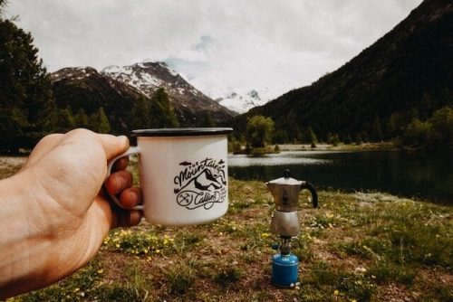 A person holding personalized travel gifts such as a custom t-shirt or a personalized mug for a road trip traveler.