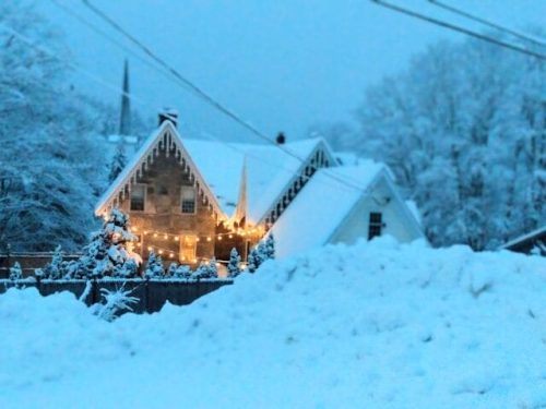 Stone cottage in snow with lights in Vermont