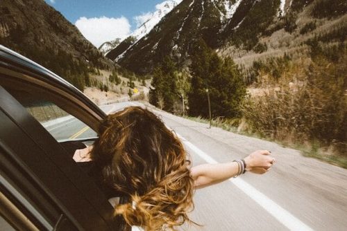 Woman riding in a car, hand feeling the wind