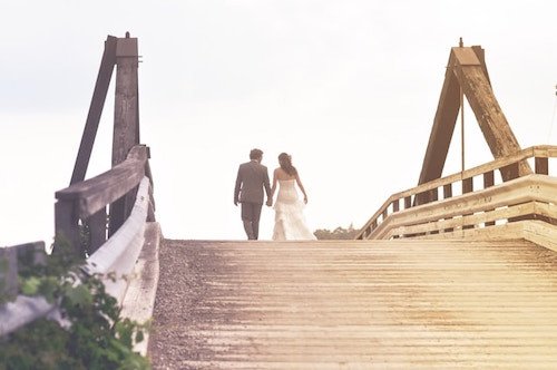 Couples walking over a bridge at the end of the reception