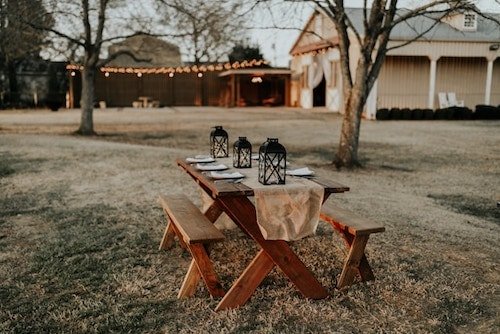 Lovely outdoor space with lanterns and picnic tables for outdoor weddings
