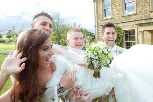 Candid shot of the bride picked up and having a laugh on their wedding day in New England