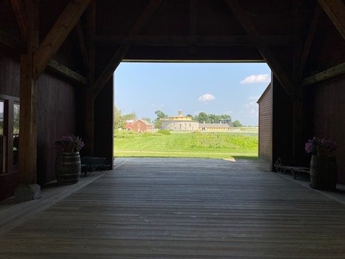 The round stone barn and landscape on a bright sunny day through the wooden entry to the Hancock Shaker Village, in Pittsfield, Massachusetts