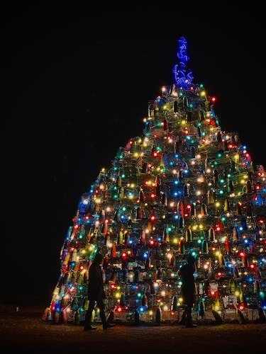 A Christmas tree of lobster traps and buoys lit up by colorful holiday lights in Mystic, Connecticut