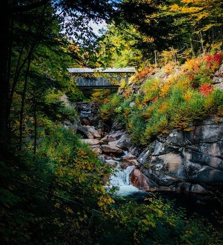 Covered bridge over a small waterfall in Flume Gorge, one of the best hiking trails in Franconia Notch State Park