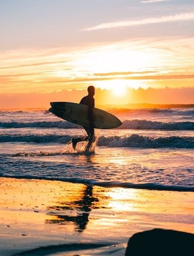 Surfer running into the sunrise at surfer's end