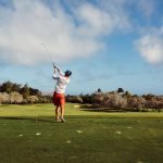 Man swinging his club on a course with friends