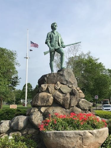 Spring flowers at the foot of a statue in Lexington, MA