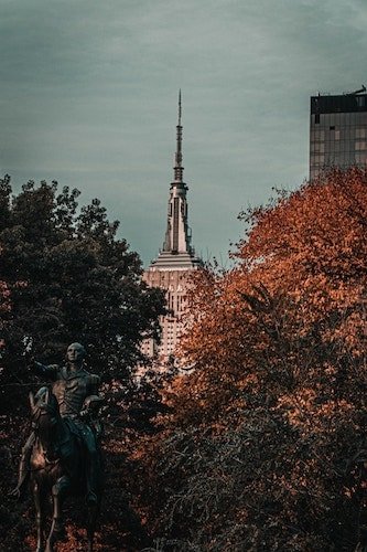 Statue of George Washington and the Empire State Building, framed in fall foliage