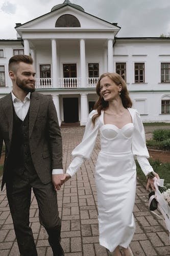 Couple walking in front of a mansion wedding venue, holding hands