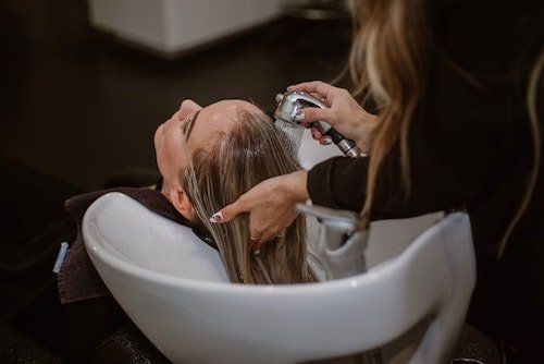 Woman getting her hair washed at a hair salon in greenwich ct as her stylists create an amazing treatment