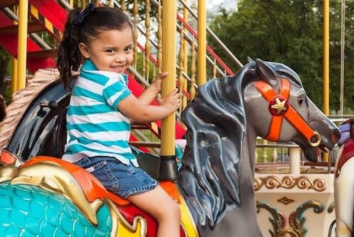 Little girl enjoying a carousel on a visit to an awesome park in CT