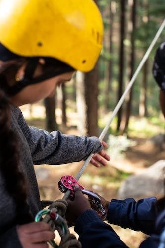 Woman getting harnessed up with color coded gears for one of the best ropes courses in Connecticut