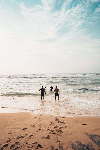Group of men running into the water at a local beach