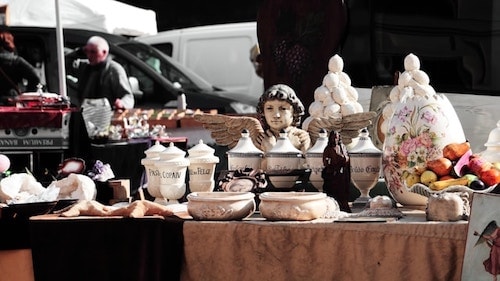 Wares out on display amidst cars with a person in the background