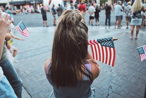 Child observing a Memorial Day parade past a new shopping plaza