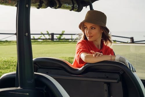 Woman in a bucket hat watching a member of her team play golf