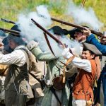 Costumed historians firing muskets at a Thursday afternoon reenactment