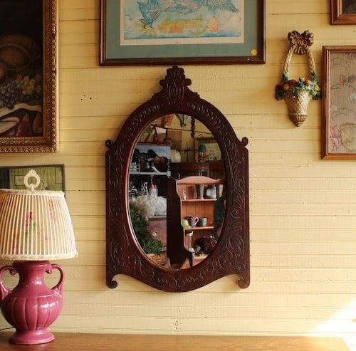 Clocks and decor on display, as seen through the glass of a mirror