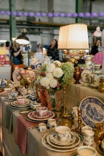 Decorated display of china, porcelain, and sterling silver sets at an antique fair on one floor on Main St