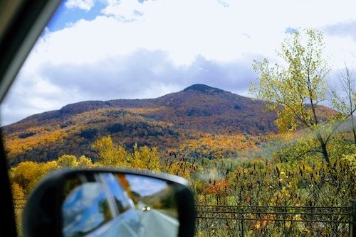 View out the window of the car of beautiful fall colors on a New England fall road trip