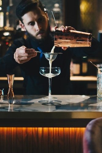 Mixologist preparing a quality cocktail with champagne on a busy week