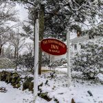 A quiet exterior winter shot of Stanton House Inn's sign: soft light, light snow on the trees