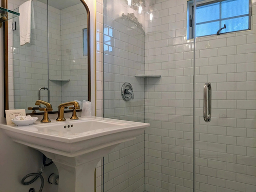 Pedestal sink and glass shower door in Room 18's bathroom