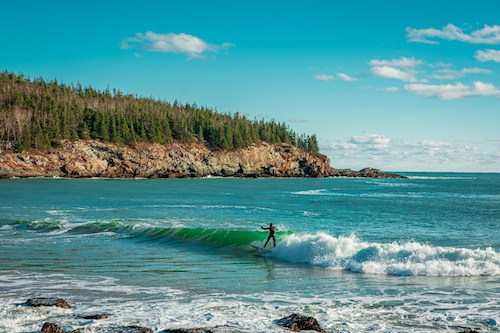 Man surfing at Sand Beach in Acadia National Park, one of the top activities among things to do in Acadia National Park