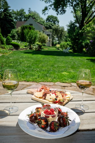 Wine, charcuterie, and chocolate covered strawberries in the back garden at Stanton House Inn with a glass of wine